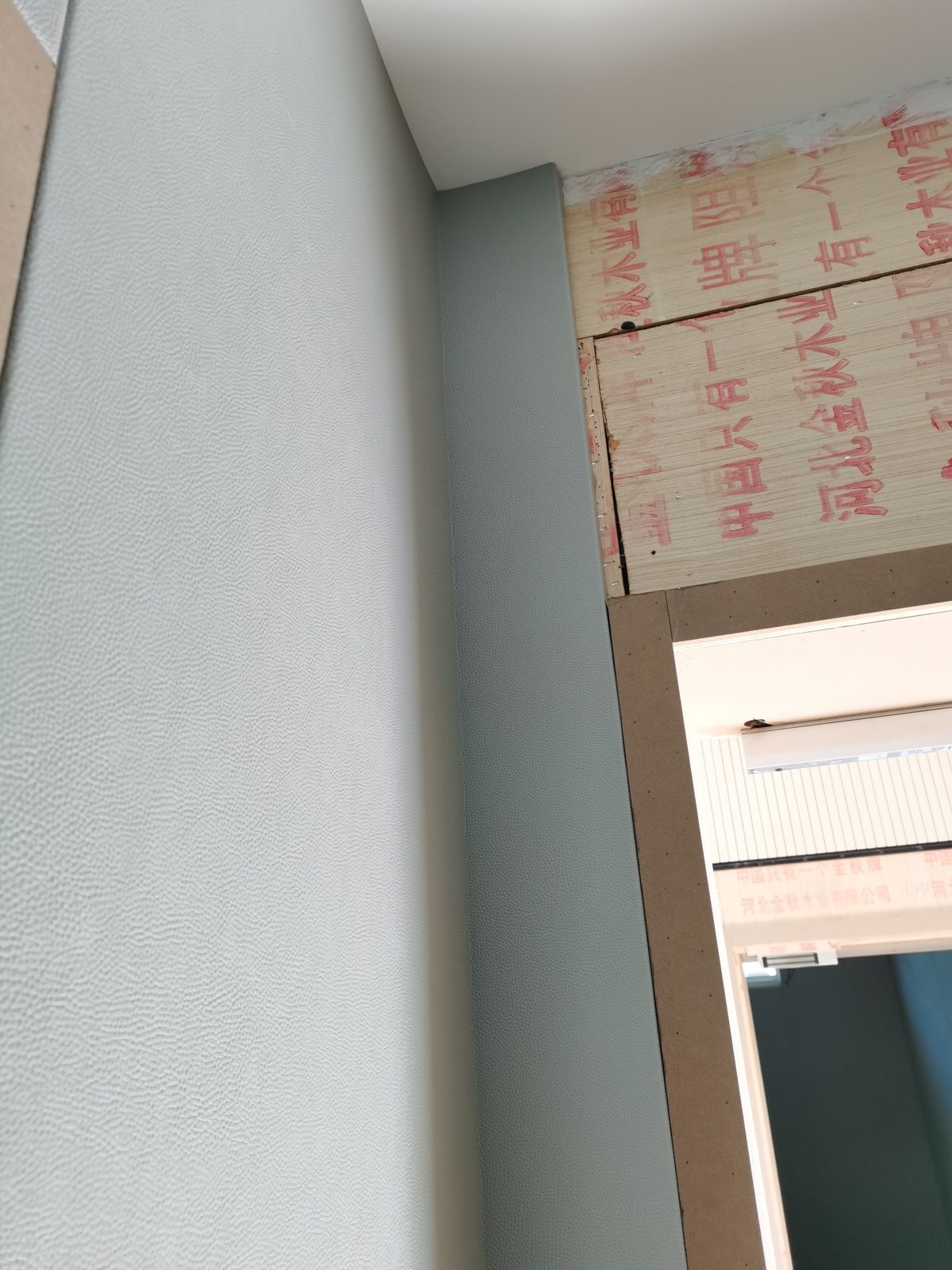 办案区审讯室白色皮革防撞软包墙面安装实景，荔枝纹软包圆角包边，防自伤施工中