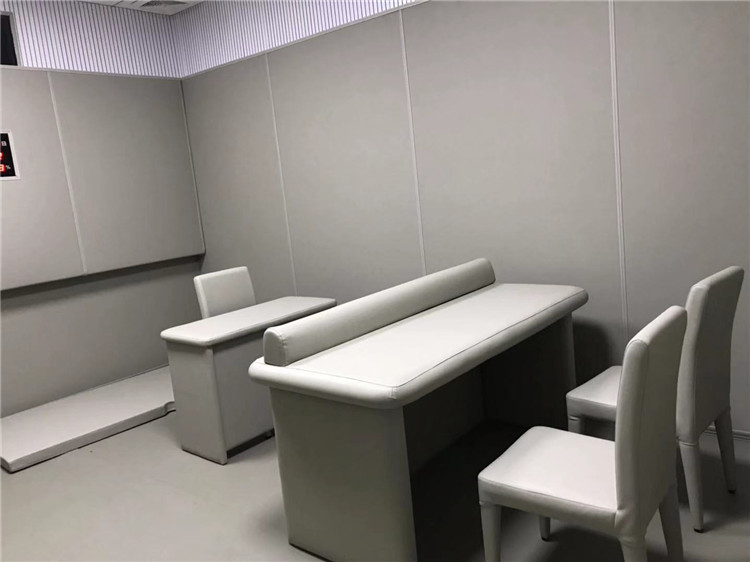 审讯室防撞软包样板间实景,白色软包墙面搭配圆角防撞桌椅,适用于公安办案区询问室