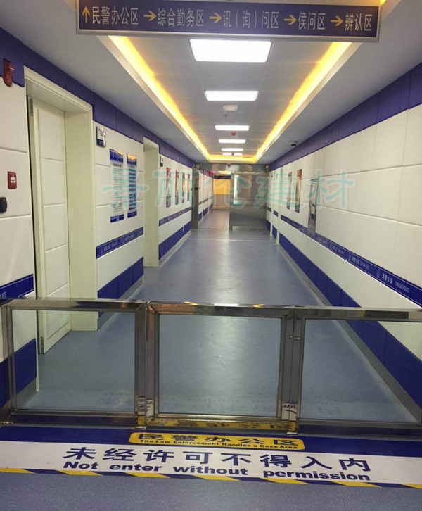 公安办案区走廊白色防撞软包墙面装修实景,蓝色饰条软包墙板防自伤设计,涵盖讯问区候问区