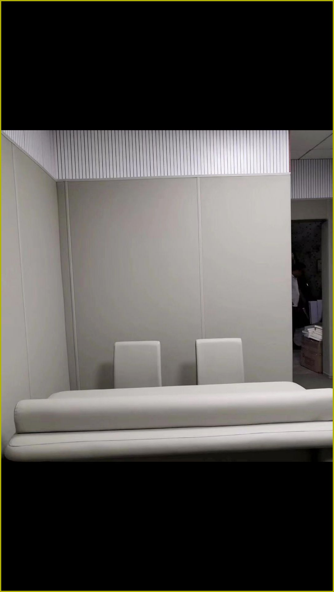 办案区审讯室白色防撞软包墙面与软包桌椅整体装修实景，高密度海绵圆角防撞设计