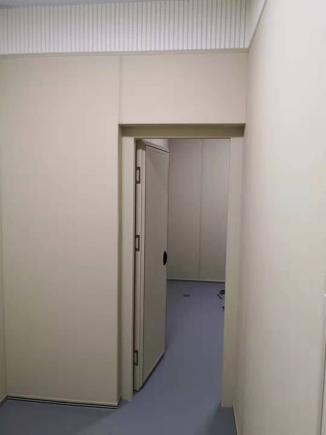 办案区审讯室米色防撞软包墙面与软包防撞门安装实景，顶部搭配穿孔吸音板，高密度海绵软包防自伤设计