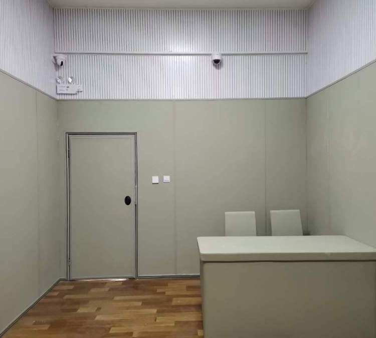 办案区讯问室防撞软包墙面整体装修实景,软包墙板搭配防撞桌椅与软包门,防自伤设计