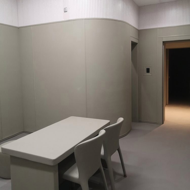 办案区审讯室米色防撞软包墙面搭配软包桌椅整体装修实景，弧形软包墙防自伤设计