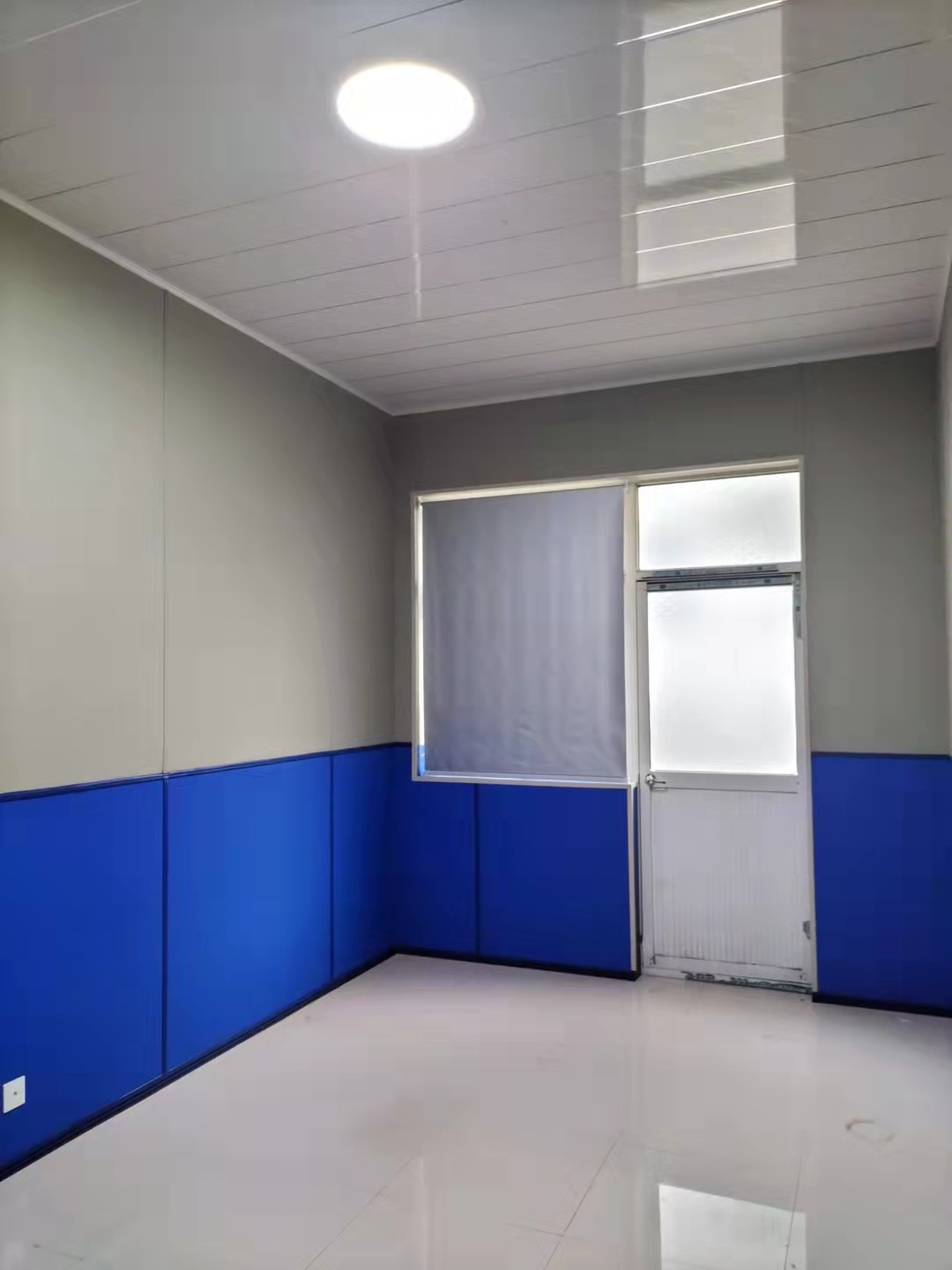 谈话室蓝色皮革防撞软包墙面安装实景,高密度海绵软包板覆盖下半墙,适用于办案区审讯室防自伤处理