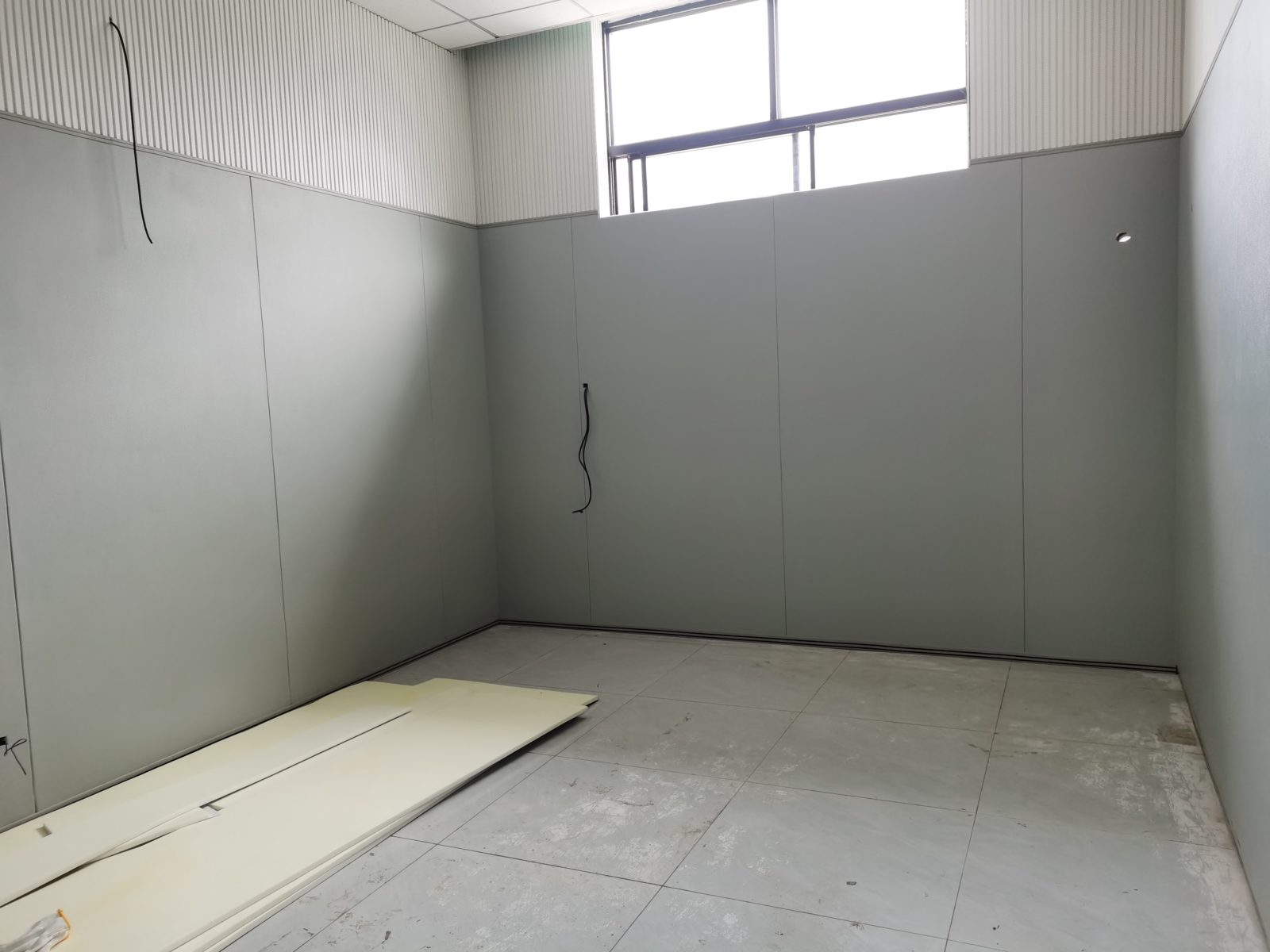 办案区审讯室灰色防撞软包墙面安装实景,高密度海绵无缝软包墙板搭配上部吸音板,防自伤防撞设计