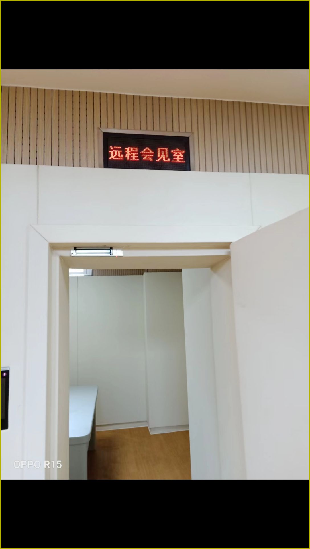 看守所远程会见室白色防撞软包墙板与防撞门安装实景，高密度海绵软包搭配顶部木条吸音板防撞防自伤处理