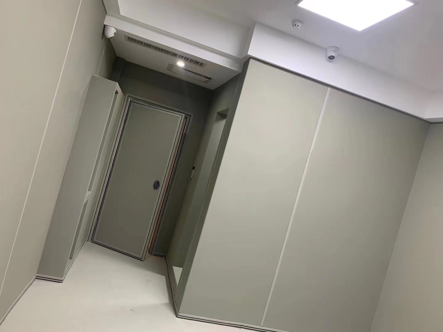 审讯室灰色防撞软包墙面整体安装实景，软包墙板搭配防撞门，高密度海绵包覆防自伤设计