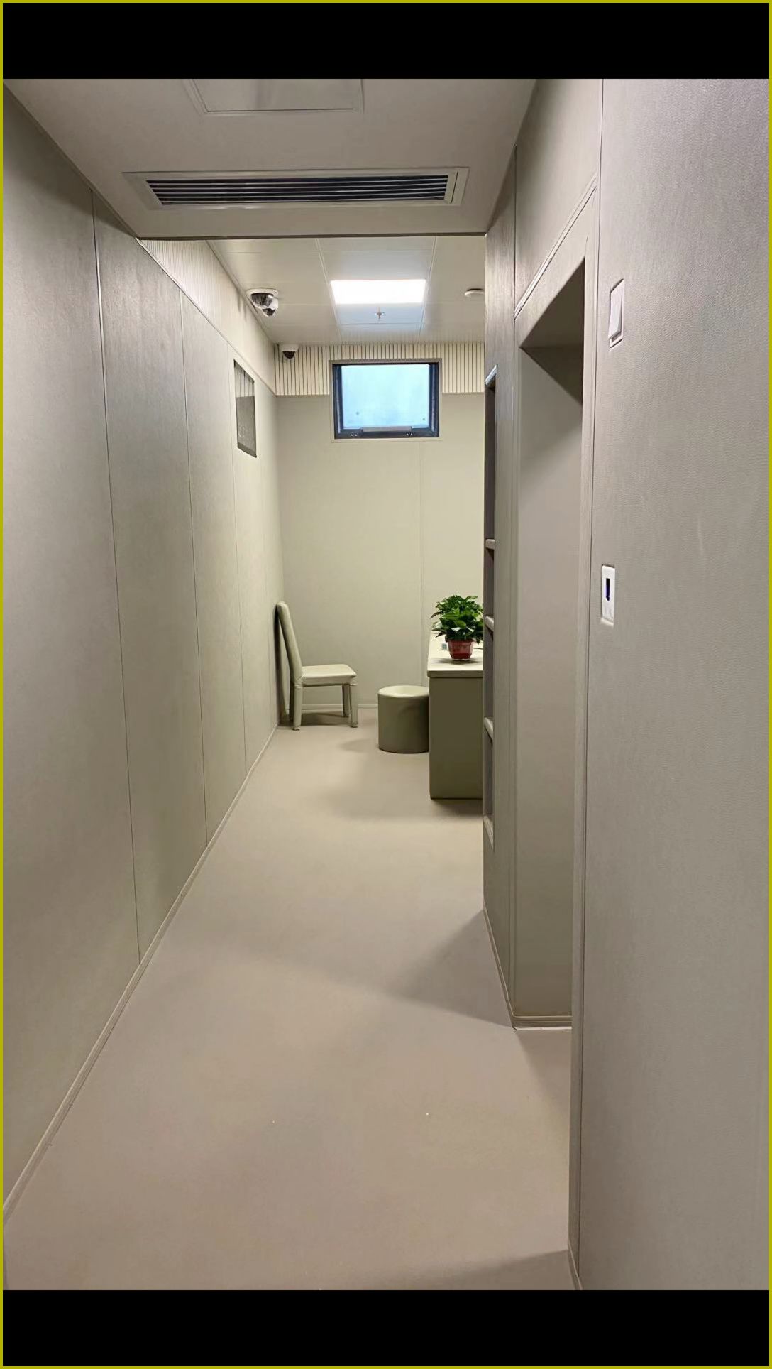 办案区谈话室米色皮革防撞软包墙面整体装修实景,搭配软包桌椅与圆角防撞家具