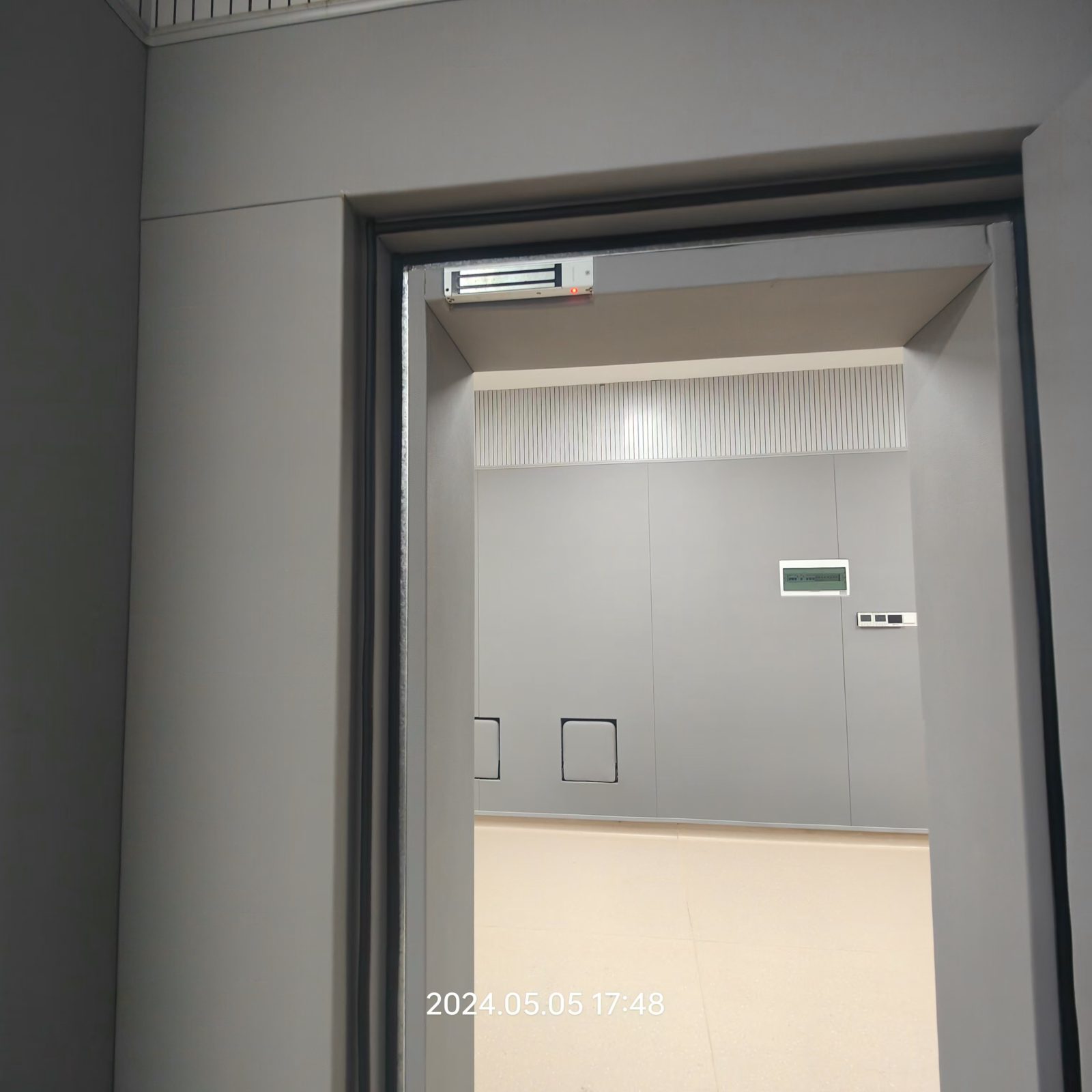 办案区审讯室灰色防撞软包墙面与电磁锁防撞门安装实景，高密度海绵软包防自伤设计