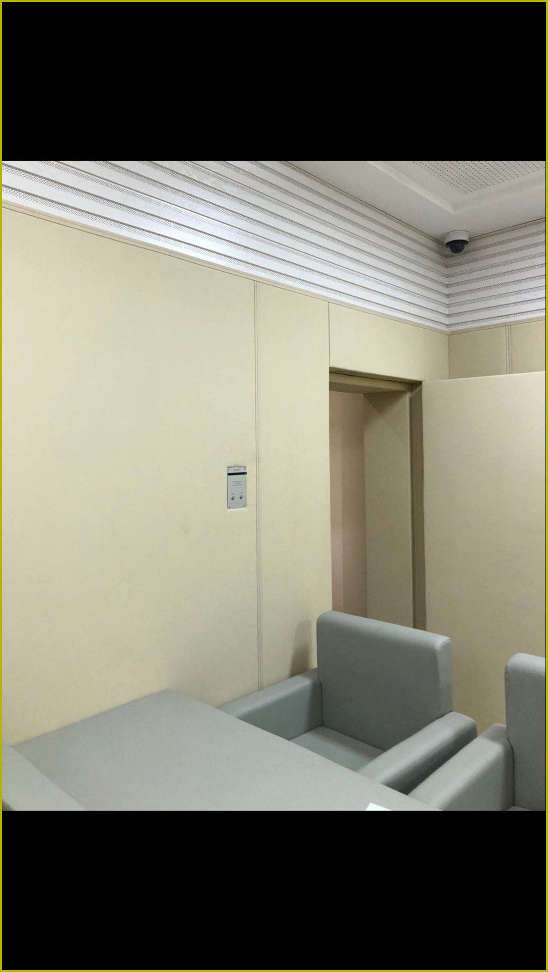 公检法办案区审讯室米色防撞软包墙面整体装修实景,搭配软包桌椅与防撞门,高密度海绵防自伤设计