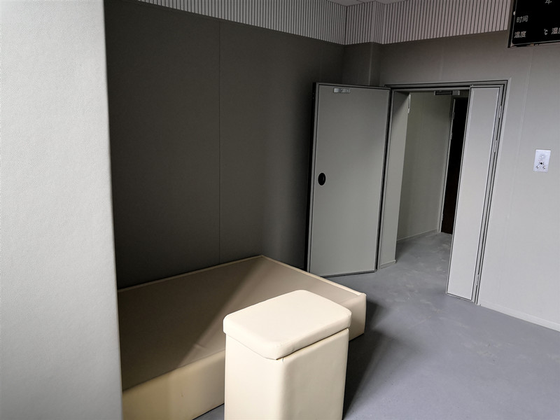 留置室防撞软包整体装修实景,米色皮革软包墙面搭配防撞床与软包凳,配软包防撞门,防自伤设计