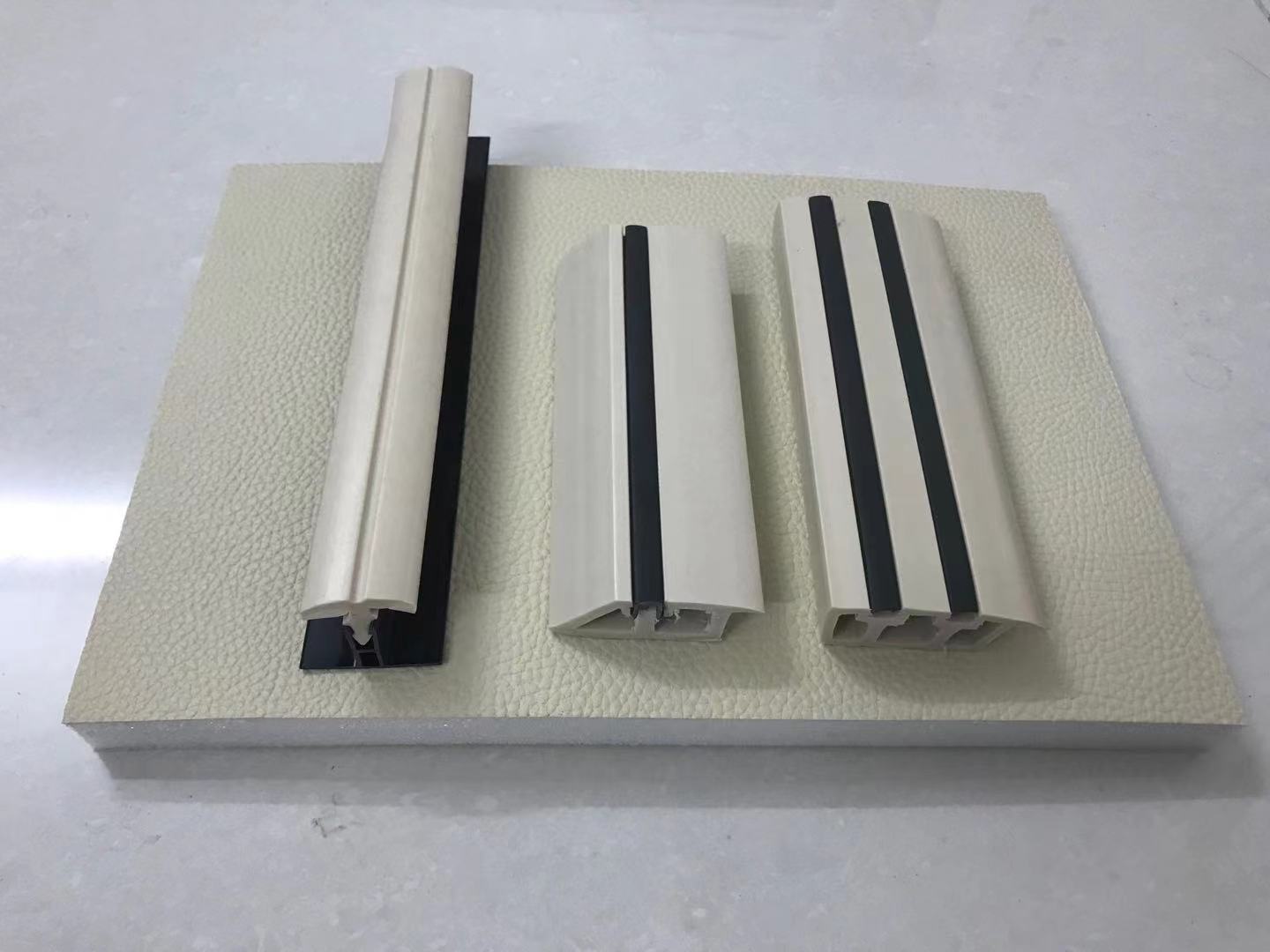 防撞软包收边条配件展示,PVC压边型材搭配米色皮革纹理软包墙板,用于办案区审讯室软包接缝收边处理