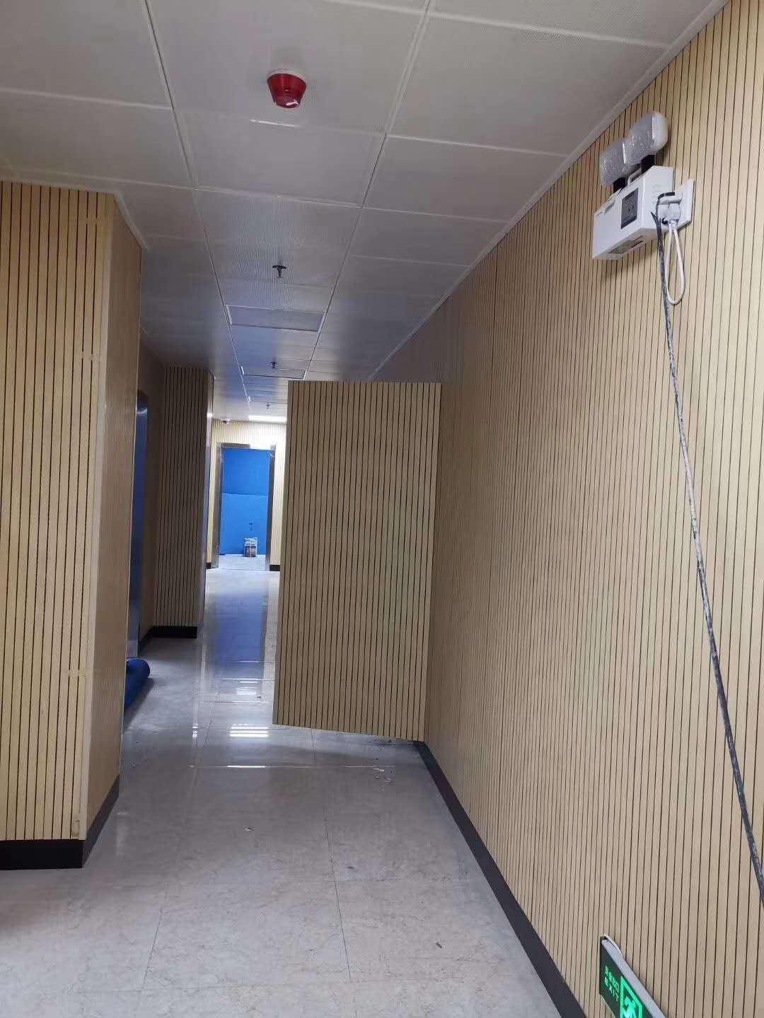 走廊墙面满铺浅木色槽木吸音板，竖条木饰面声学板材安装实景，吸音降噪装饰