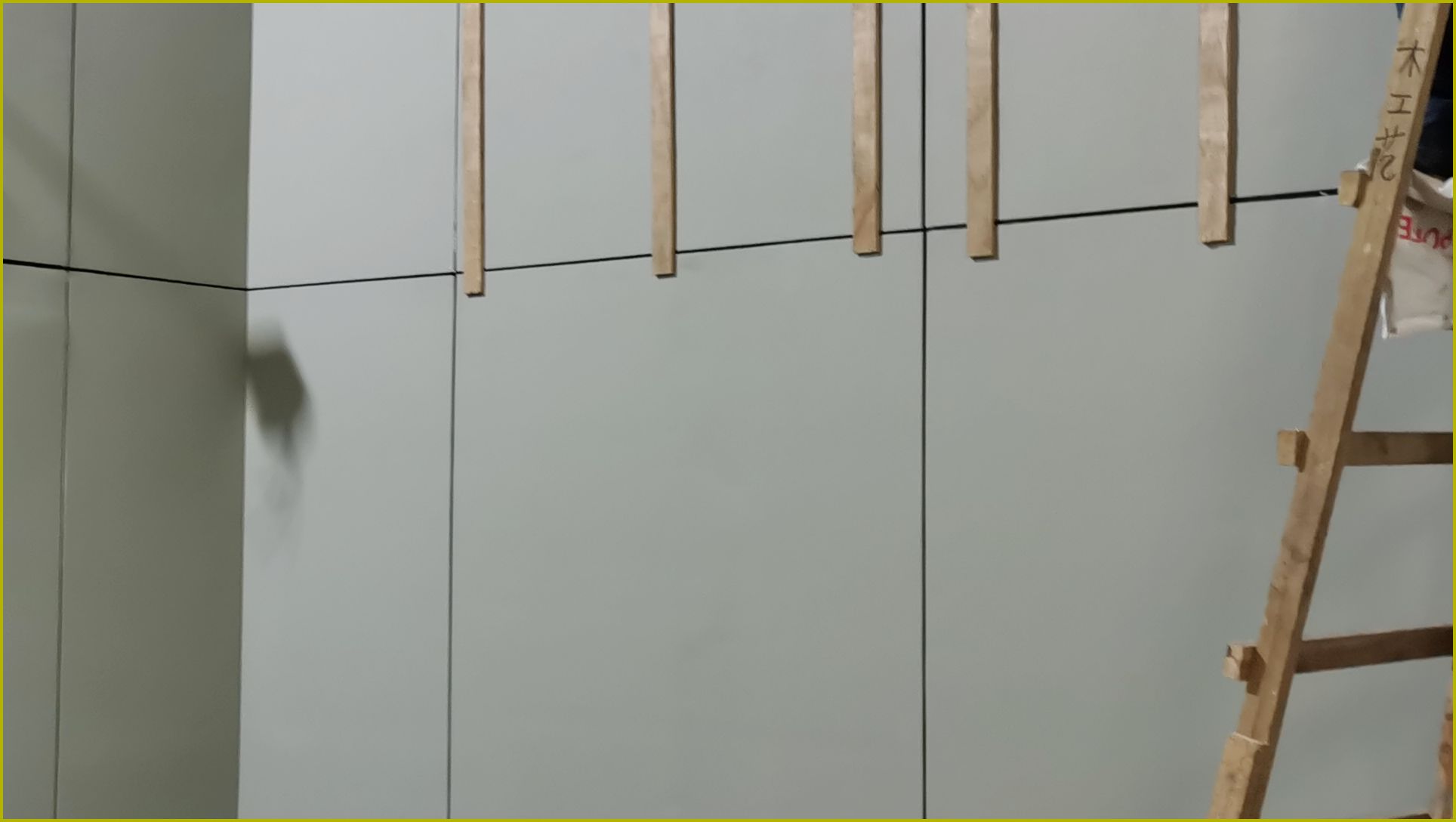 隔音工程施工实景，墙面安装竖向木龙骨条带作为声学装饰板基层结构